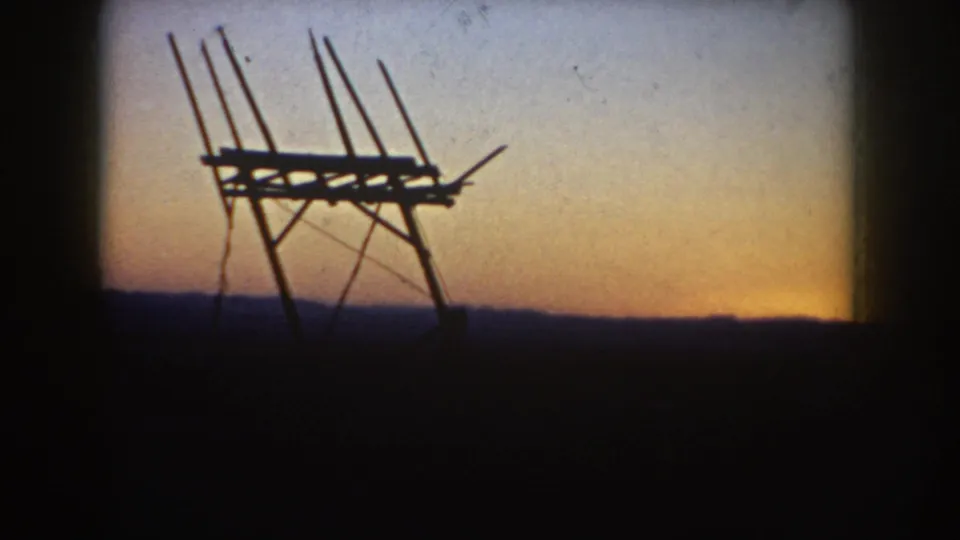 Static 8mm view from South Dakota in 1953 with a dark antenna-like frame set against a blue-orange evening sky.