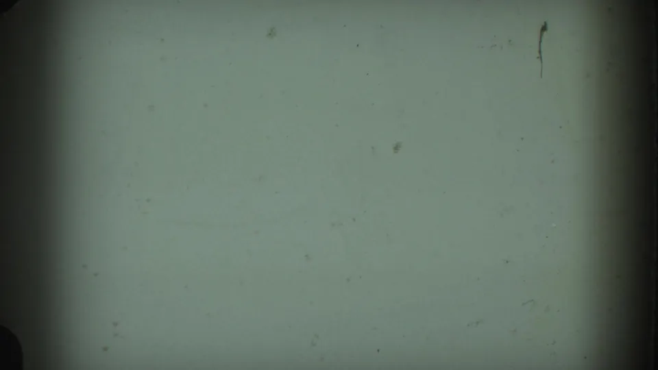 A mostly blank 8mm frame with pale green exposure, dark vertical edge shading, and visible dust or film marks.