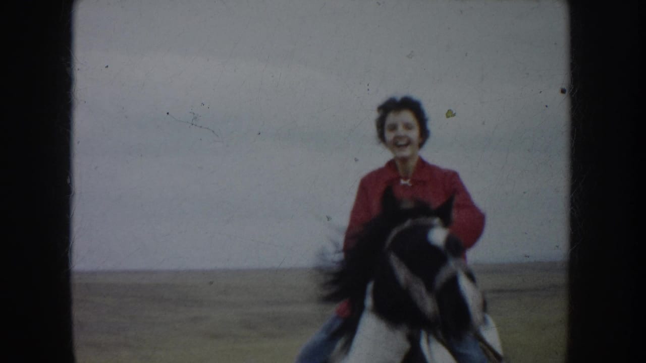 The smiling rider comes near the camera on horseback, with the open South Dakota field behind them.