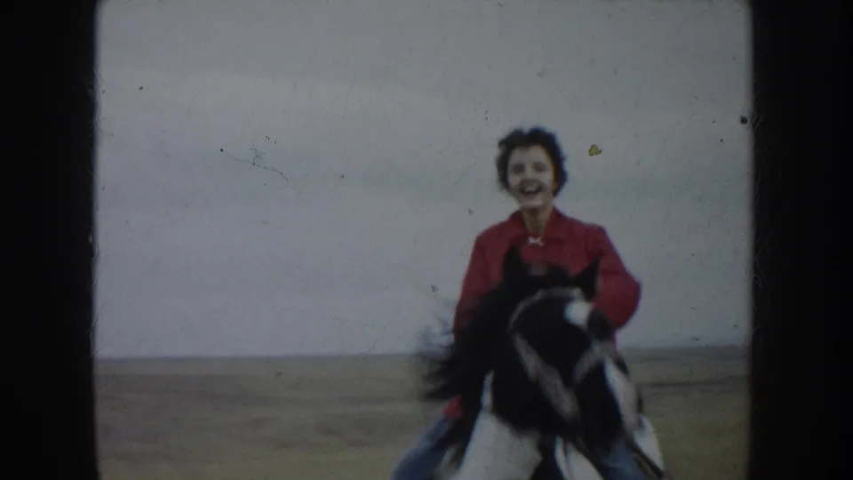 The smiling rider comes near the camera on horseback, with the open South Dakota field behind them.