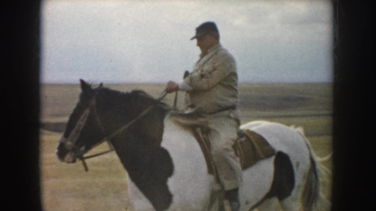 A closer 1953 South Dakota frame shows the rider in a cap holding the reins while seated on the pinto horse in the field.