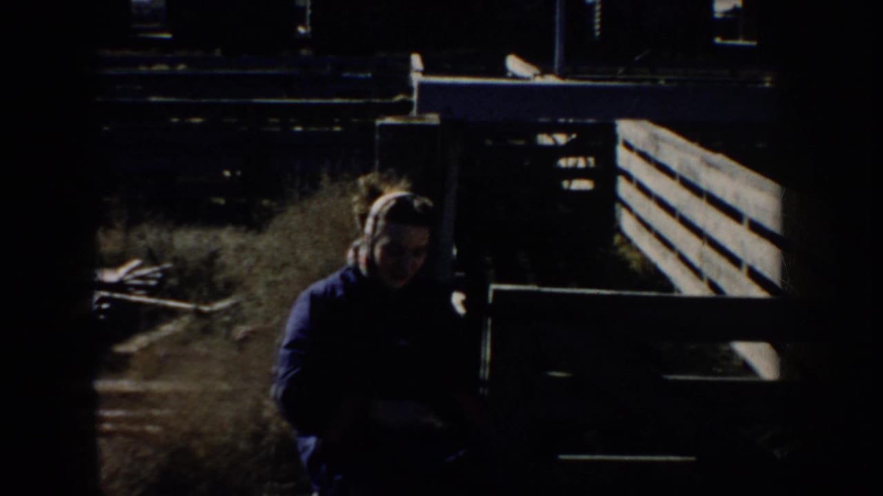 Girl in a dark coat appears near livestock-yard fencing in 1953 South Dakota home-movie footage.