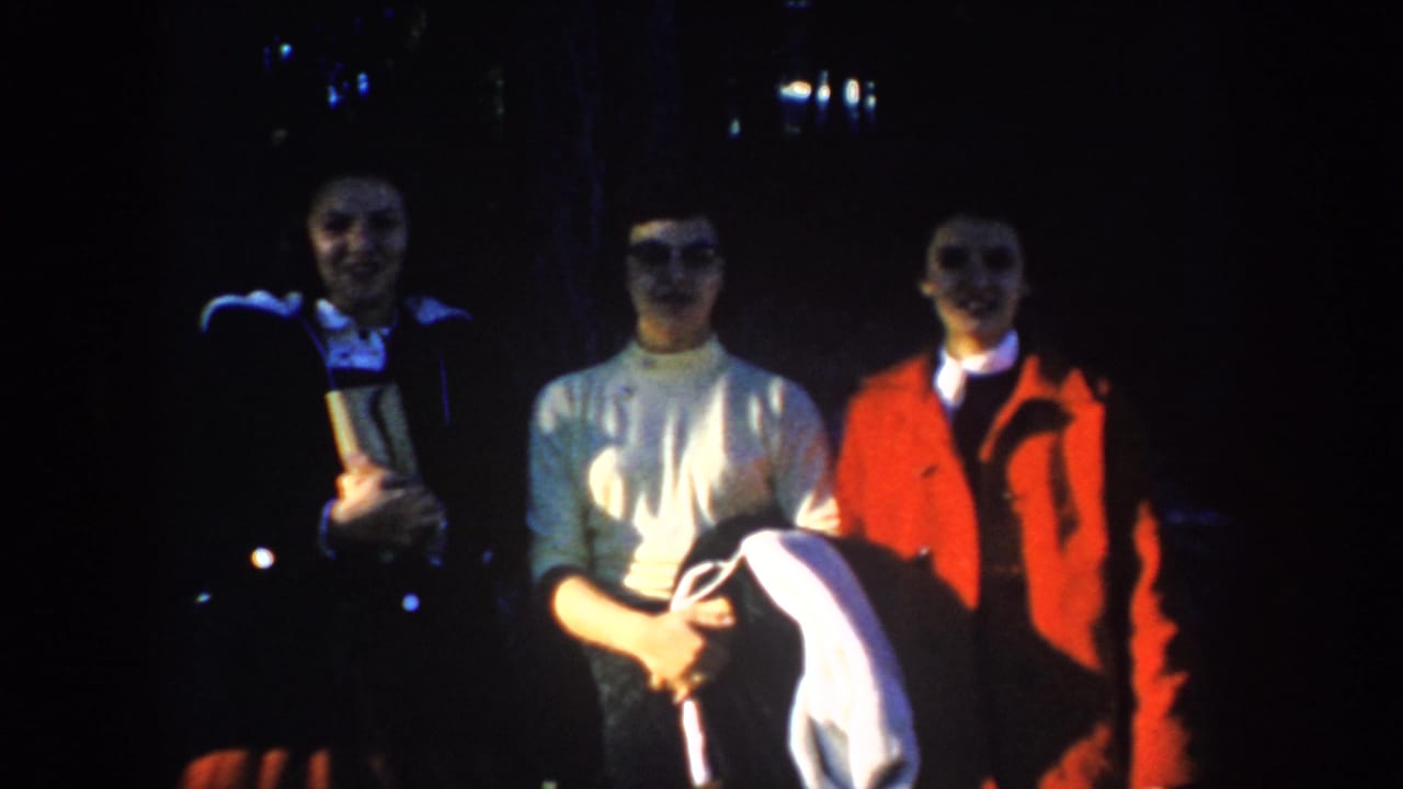 Three women continue posing outdoors at night in coats and sweaters.