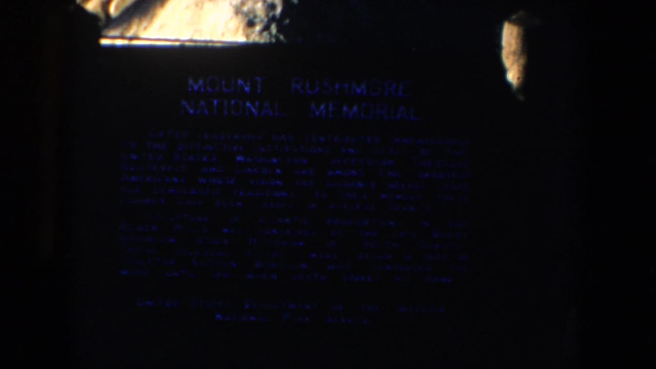 The official Mount Rushmore National Memorial plaque appears in grainy nighttime 8mm footage.