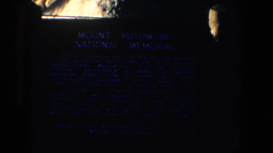 The official Mount Rushmore National Memorial plaque appears in grainy nighttime 8mm footage.