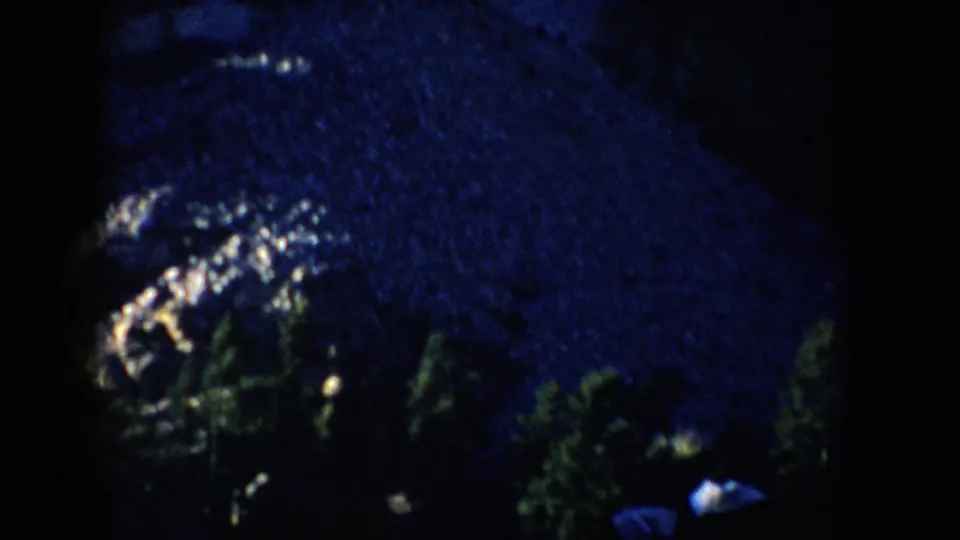 1953 South Dakota 8mm frame with dense snow-covered trees and a faint small figure or object near the lower edge.
