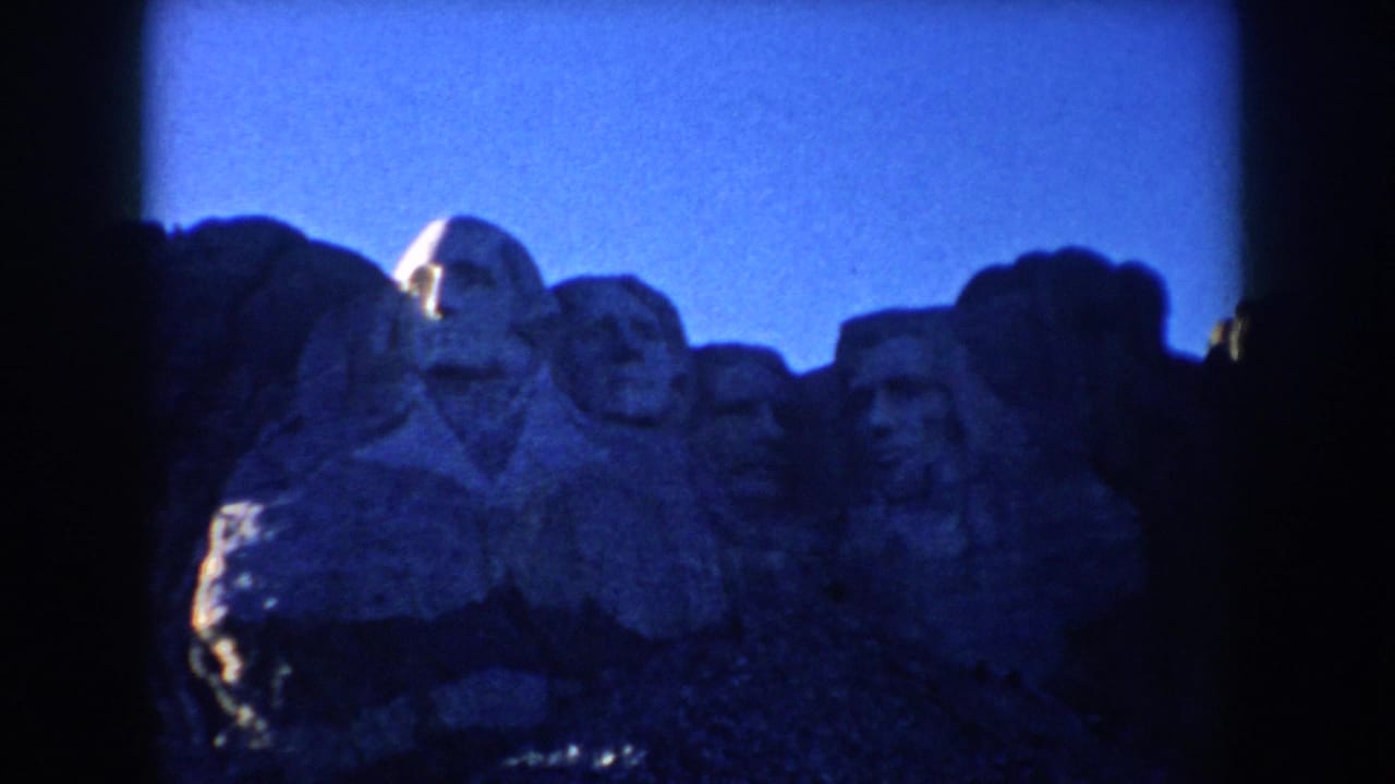 1953 South Dakota frame with Mount Rushmore visible in soft focus through darkened home-movie film edges.
