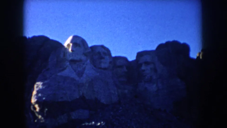 1953 South Dakota frame with Mount Rushmore visible in soft focus through darkened home-movie film edges.