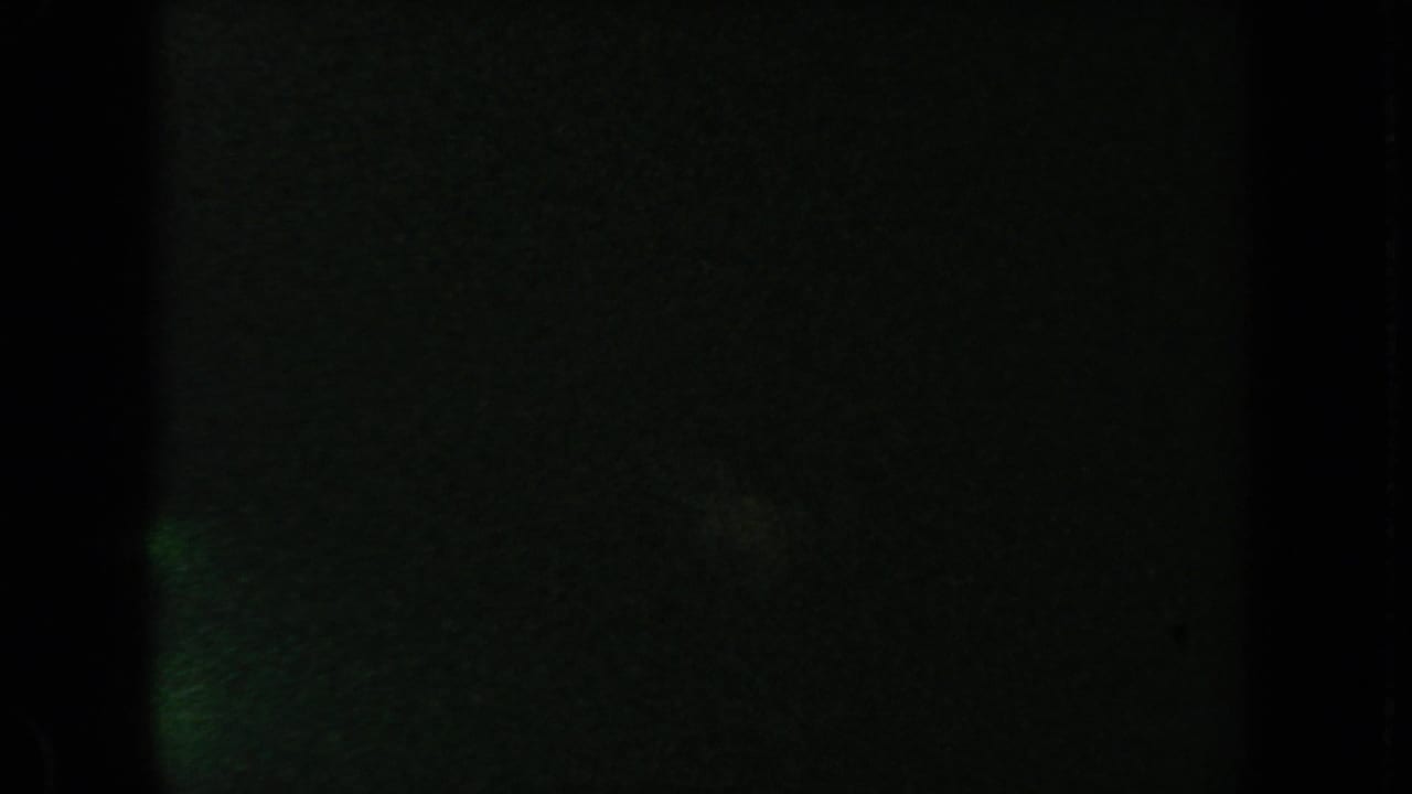 Mostly black frame with faint greenish exposure and film edge markings.