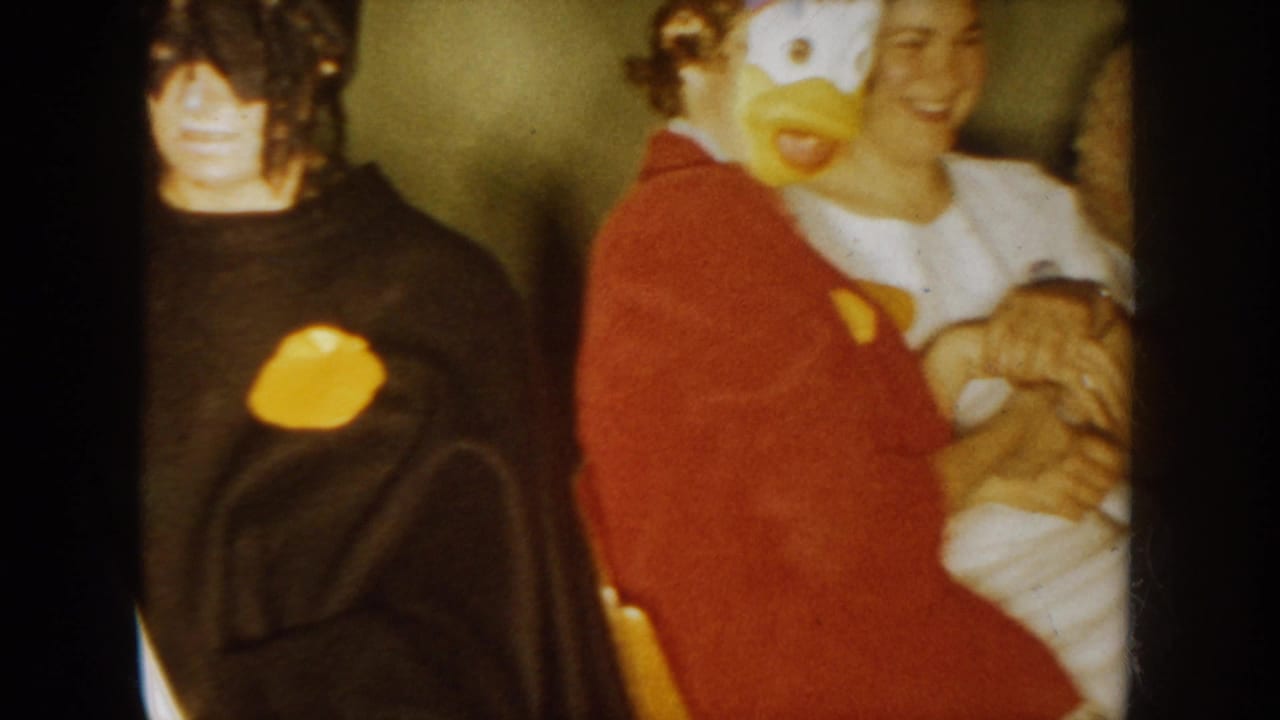 Costumed party guests pose near a person wearing a yellow duck mask.