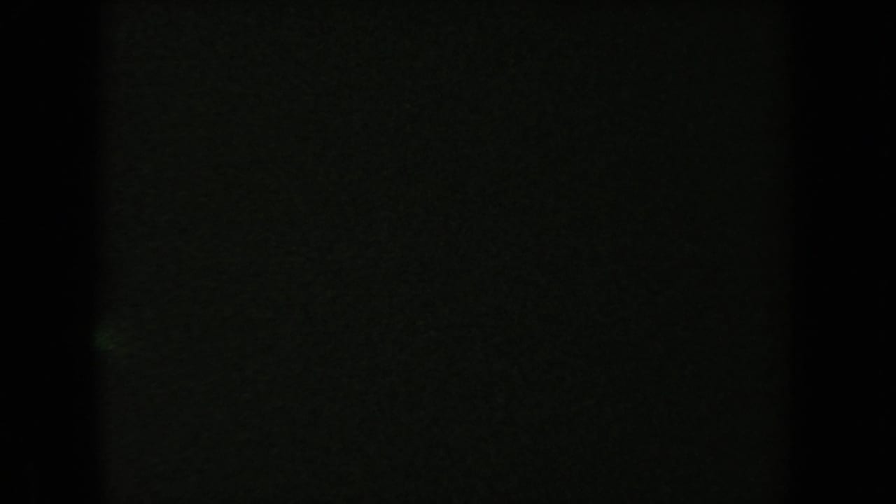 Mostly dark frame with faint greenish film texture and little visible detail.