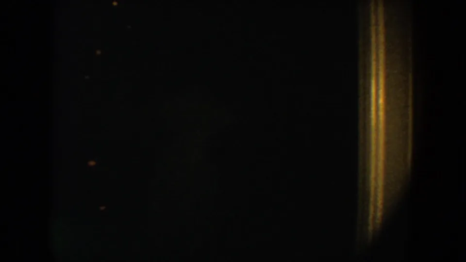 1954 South Dakota 8mm frame with a dark peephole-like view, warm trim at right, and visible film specks.