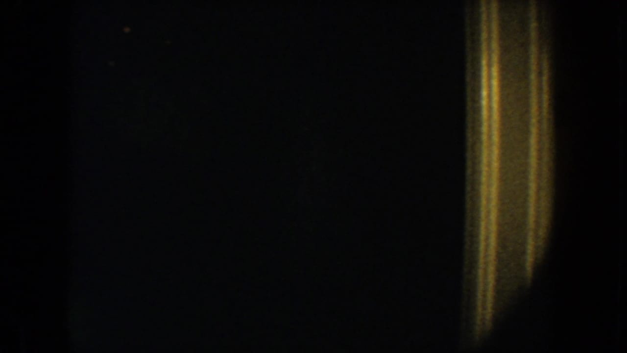 1954 South Dakota 8mm frame showing a dark interior doorway with warm yellow trim and very low visible detail.