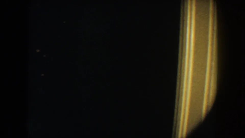 South Dakota 1954 8mm frame showing a dark private interior and warm yellow doorway trim at the right edge.