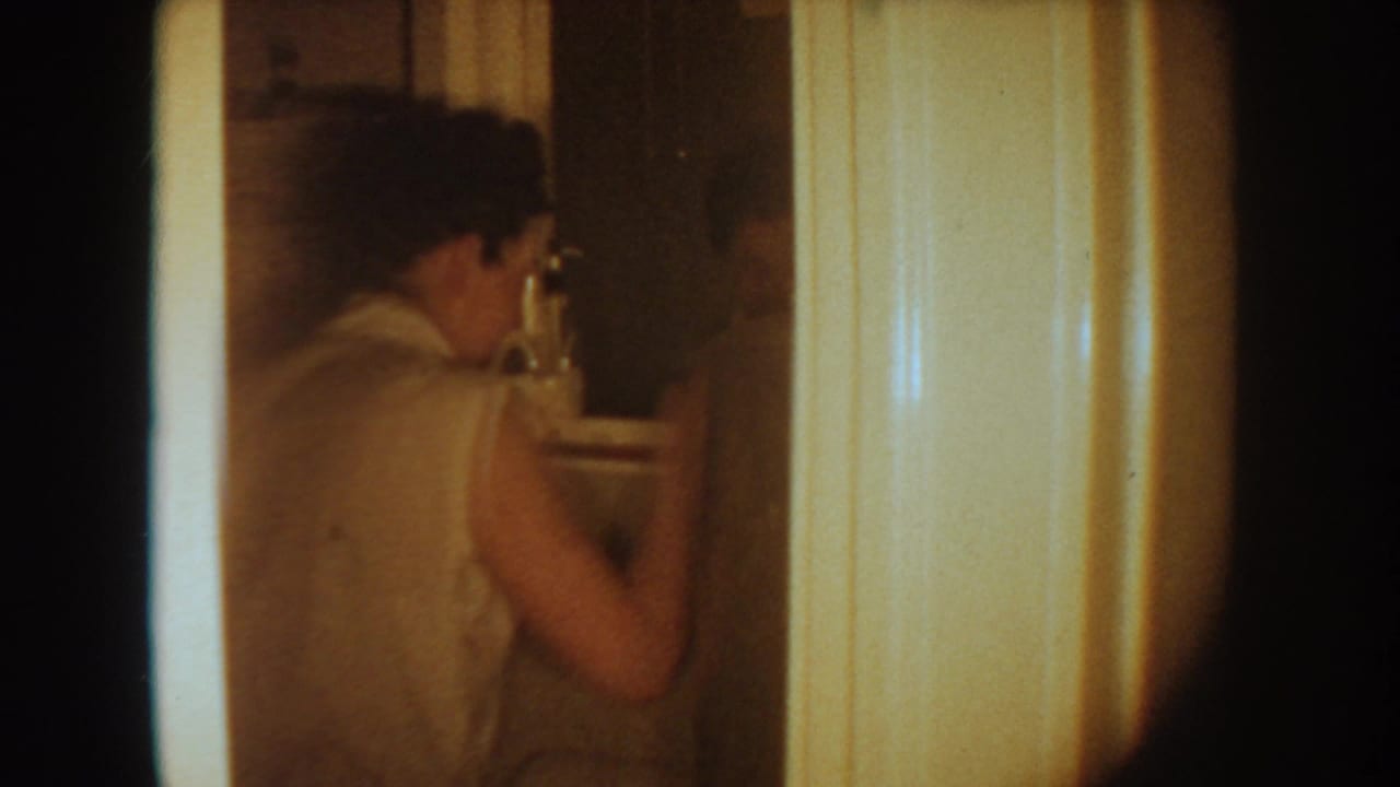 A woman in a light sleeveless top stands near a bathroom sink in a 1954 South Dakota home interior.
