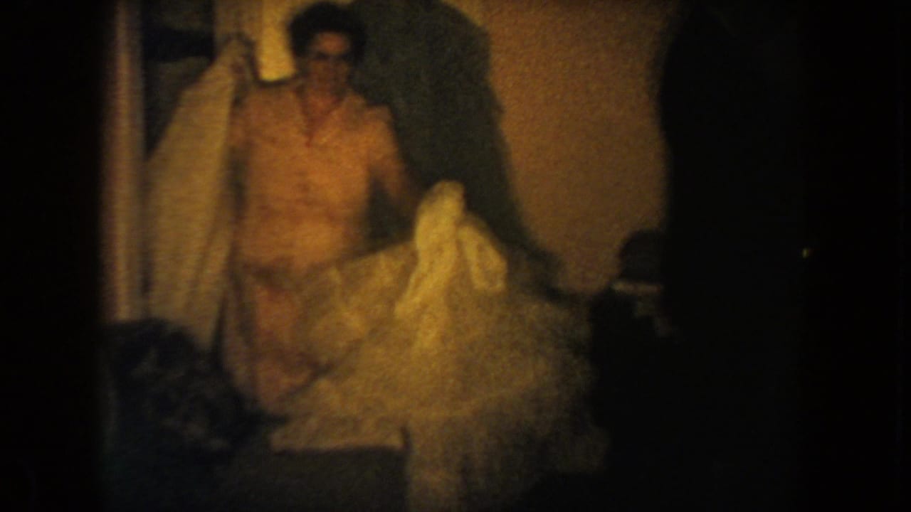 Woman standing in a doorway while holding a pale frilled dress.