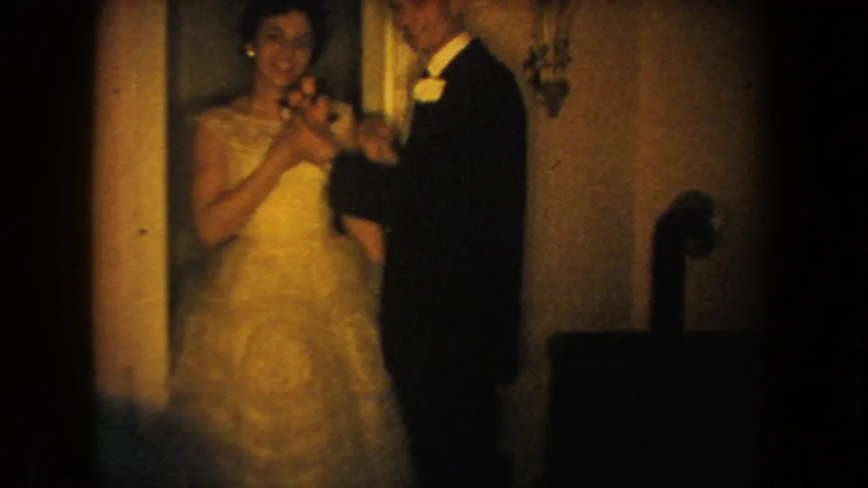 1954 South Dakota 8mm frame of a bride and groom handling a corsage or small flower indoors before a wedding.