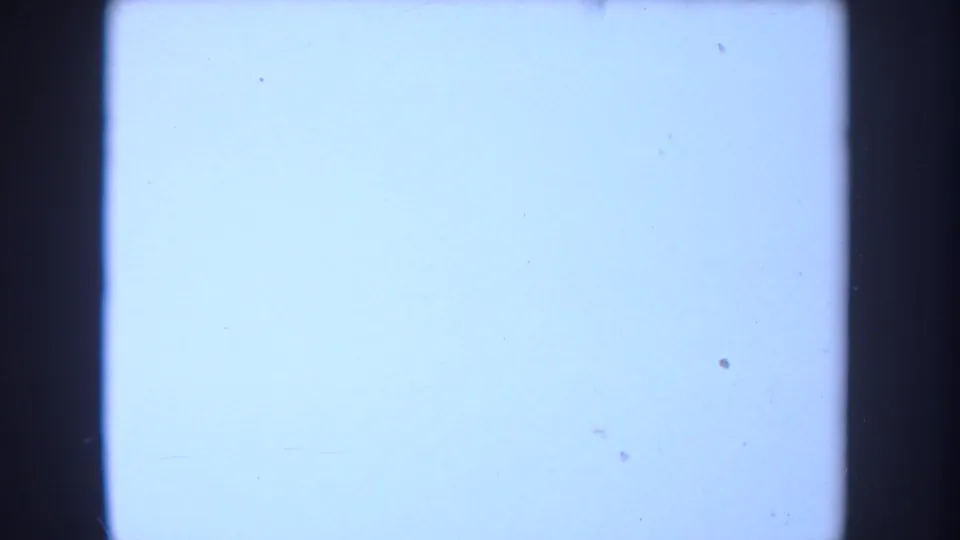 Overexposed 8mm frame at the end of the clip, showing a pale blue-white field with a dark vertical film edge.