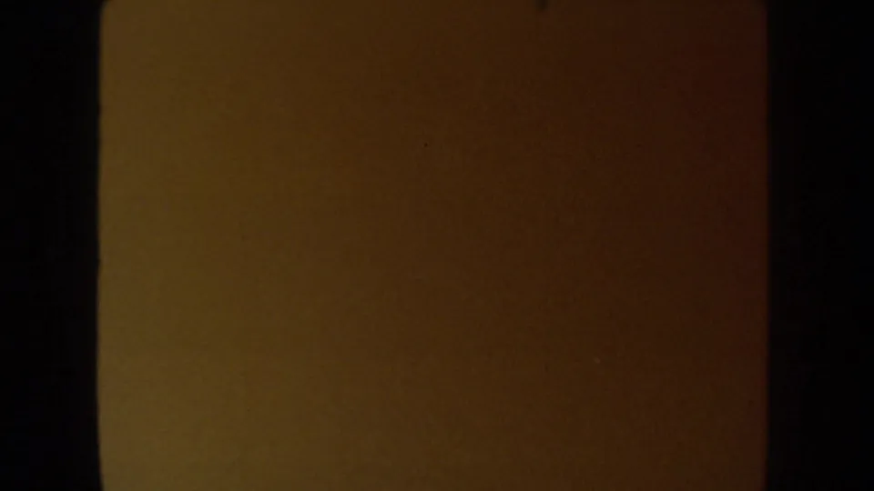 A dark, warm-toned 8mm frame from the 1954 South Dakota wedding clip, likely leader or underexposed transition footage.