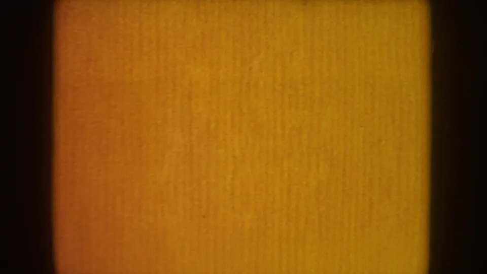 Warm amber 8mm frame from the South Dakota wedding home movie, with film grain and no distinct figures visible.