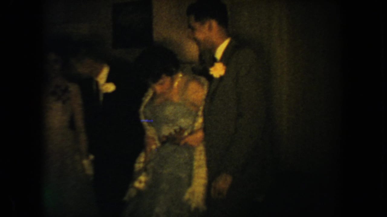 A woman in a formal gown stands near a tall man in a suit during the reception.