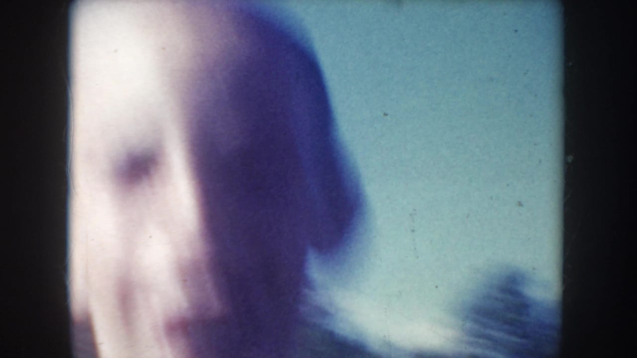 Close 8mm frame from the South Dakota lake scene showing a swimmer's face above the water, softened by focus and film color shift.