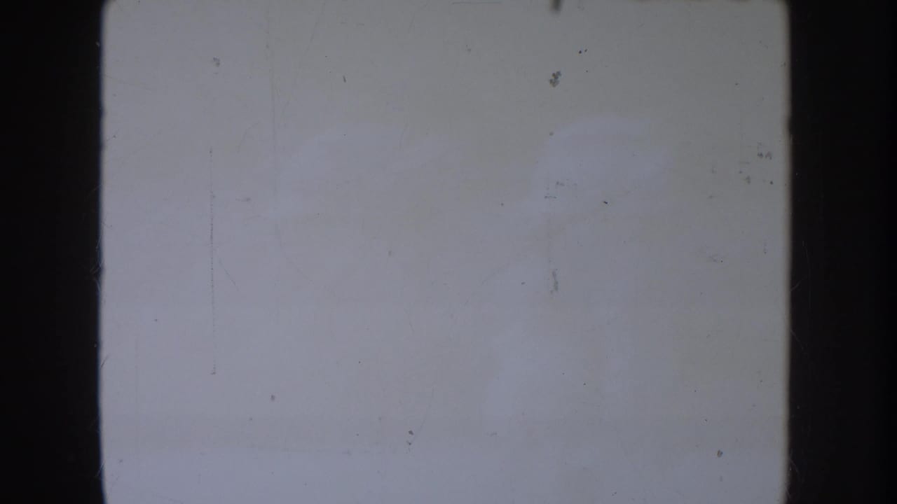 Mostly blank pale film frame with dark borders and visible dust marks.