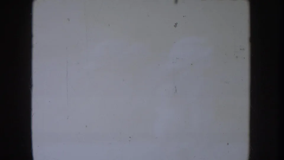Mostly blank or overexposed 8mm frame from the 1954 South Dakota reel, with film borders, dust and faint surface marks visible.