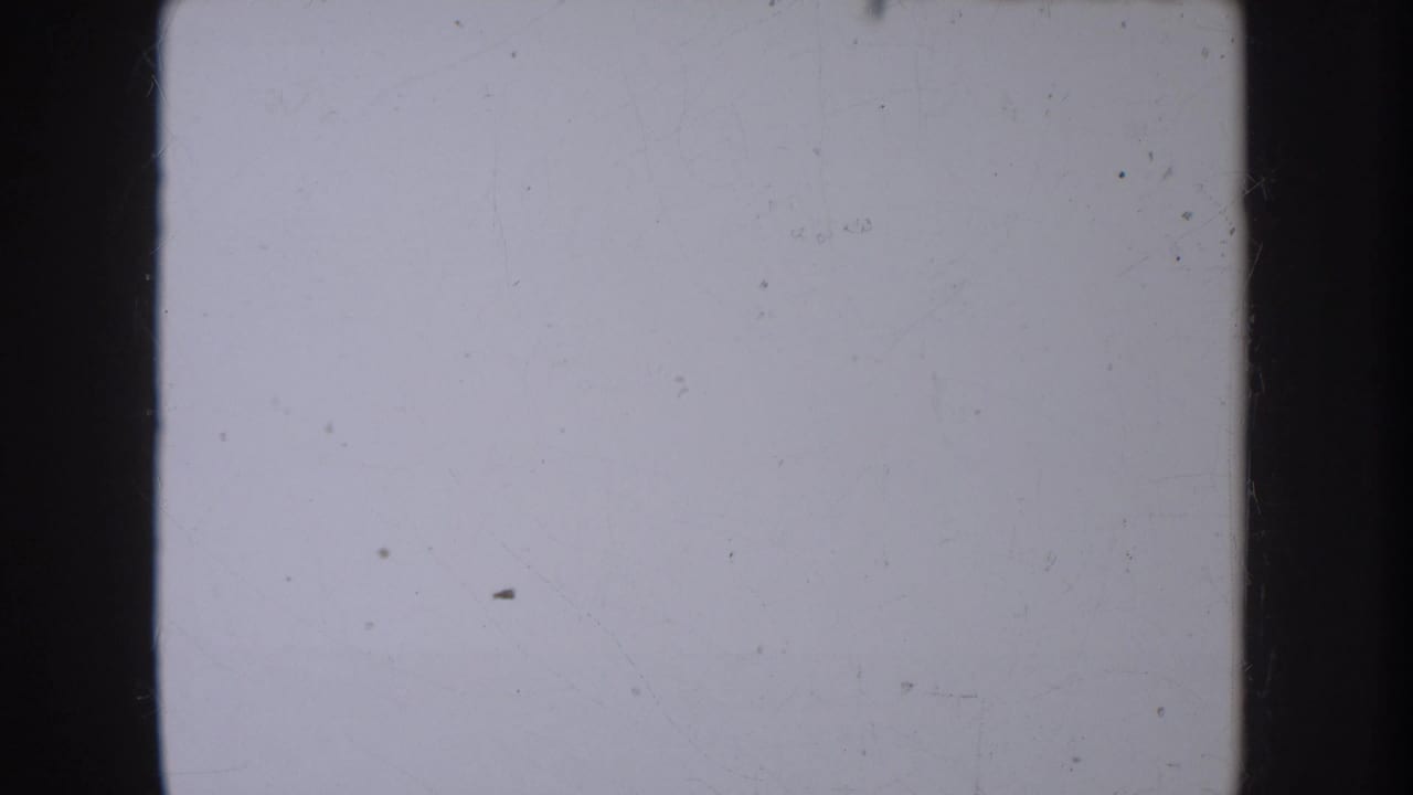 Mostly blank or overexposed 8mm frame from the South Dakota home movie, showing dust, faint scratches and dark film edges.