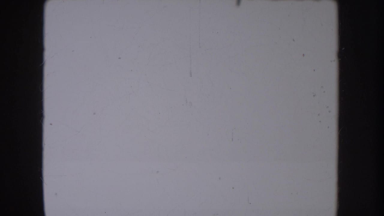 A pale, scratched 8mm frame from the clip opening, bordered by dark gate edges with no distinct person or landscape visible.