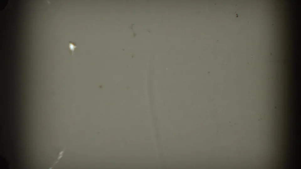 Pale wall or projection surface in a 1954 South Dakota 8mm frame, with dark edge vignetting and visible film dust.