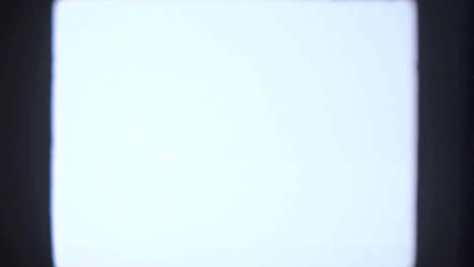 Blank bright projection screen or illuminated surface in the 1954 South Dakota classroom footage, framed by dark edges.