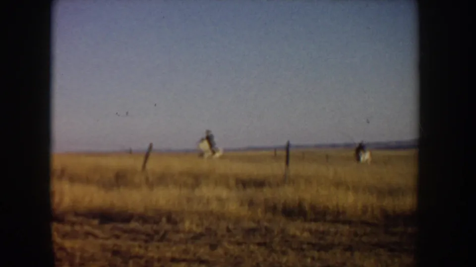 Near the end of the Idaho 8mm clip, the riders are distant figures crossing open grassland beneath a broad sky.