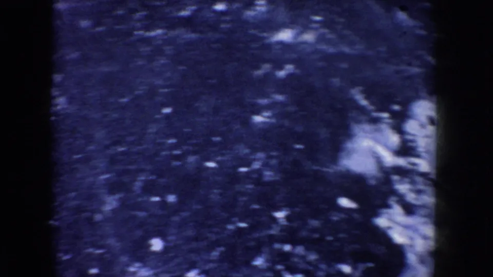 Close view of a frozen lake surface in the 1955 Idaho footage, with a fish visible near the right edge.