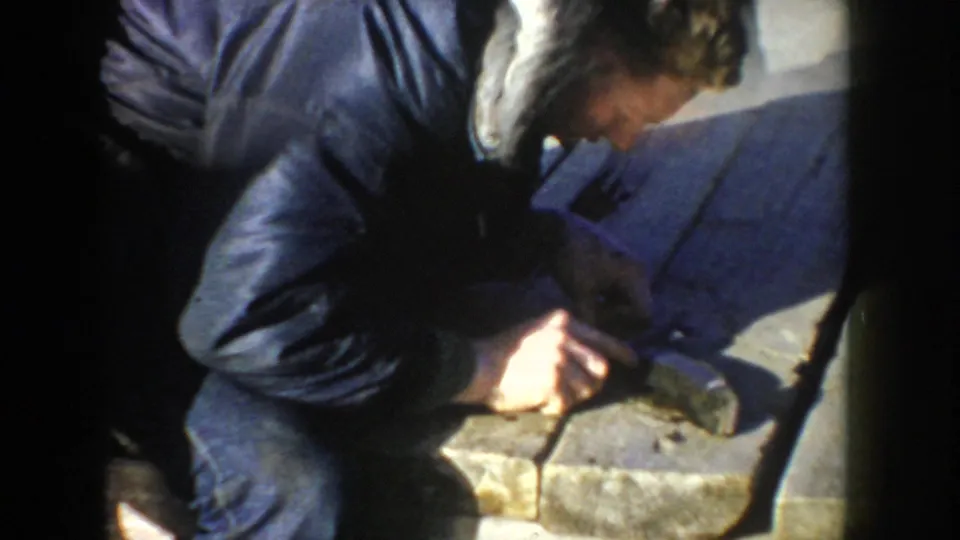 In the 1955 Idaho footage, a man crouches over a fish on a dock, apparently beginning to clean or gut it by hand.