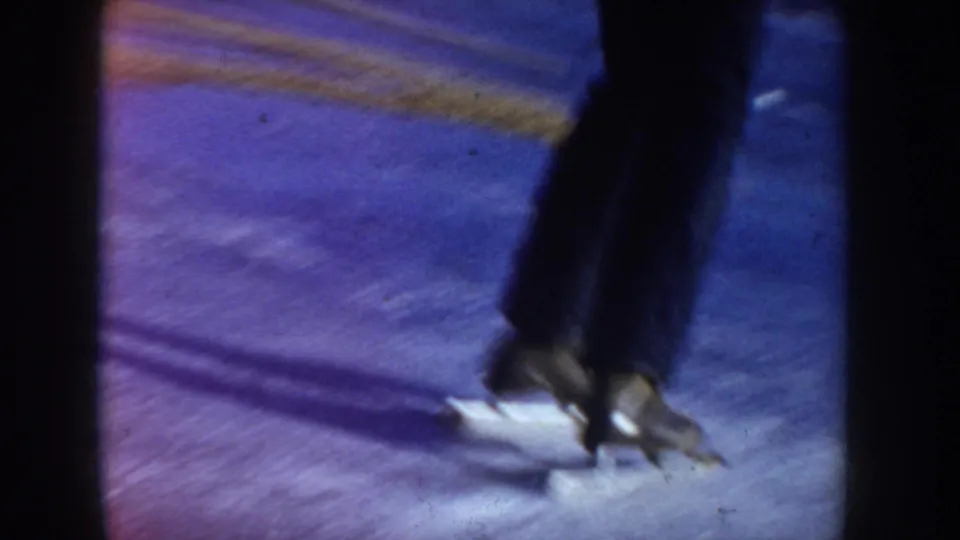 Extreme close-up of ice skate blade on ice showing a pronounced blue-purple emulsion cast; 8mm home movie, Idaho, circa 1955.