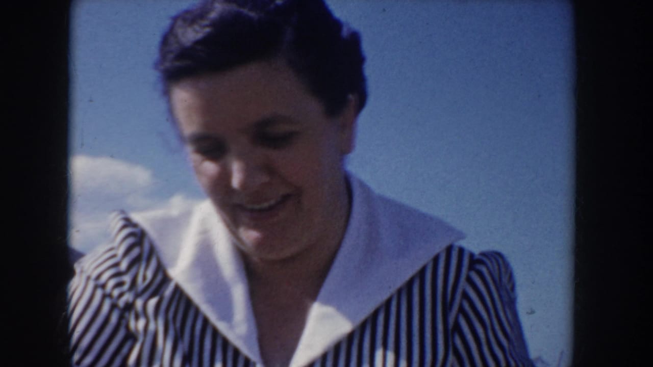 Portrait close-up of a woman in a 1950s black-and-white striped dress with wide white collar, smiling warmly, at an Idaho outdoor picnic circa 1955, clear blue sky and light clouds behind her.