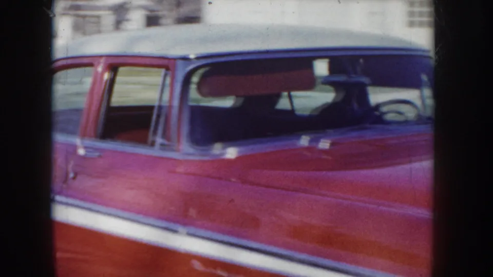 Tight shot of the roofline and chrome body trim of a mid-1950s red and white two-tone American sedan, circa 1955 Idaho, USA.