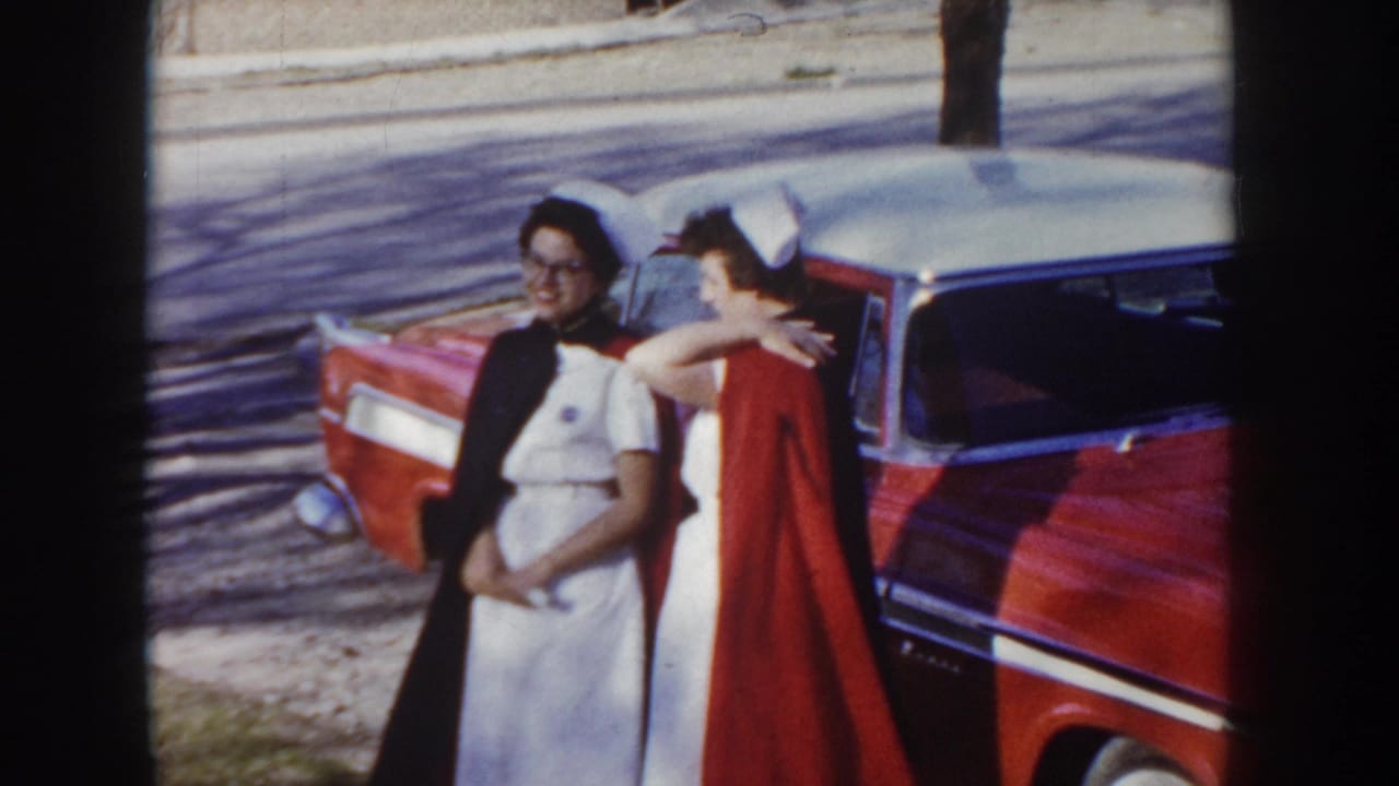 Two women pose beside a red and white two-tone sedan in what appears to be Idaho, circa 1955; one wears a white nurse uniform and cap.