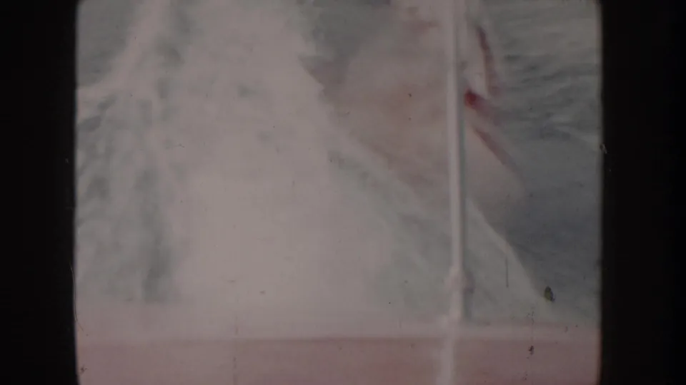 Close-up of what appears to be a flag or canvas billowing in wind on a boat, heavily overexposed 8mm frame, circa 1955.