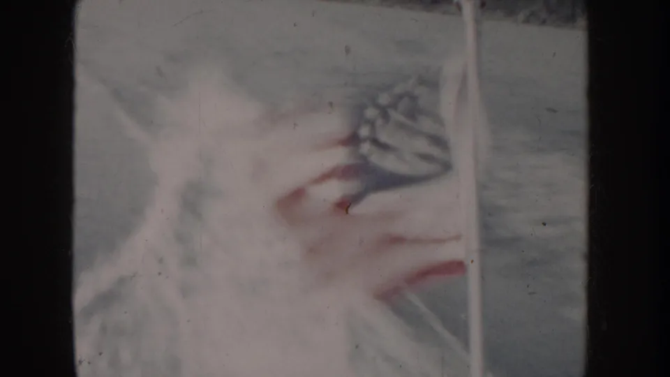 Close-up of what may be an American flag billowing from a boat, heavily overexposed 8mm frame, Idaho waterway circa 1955.