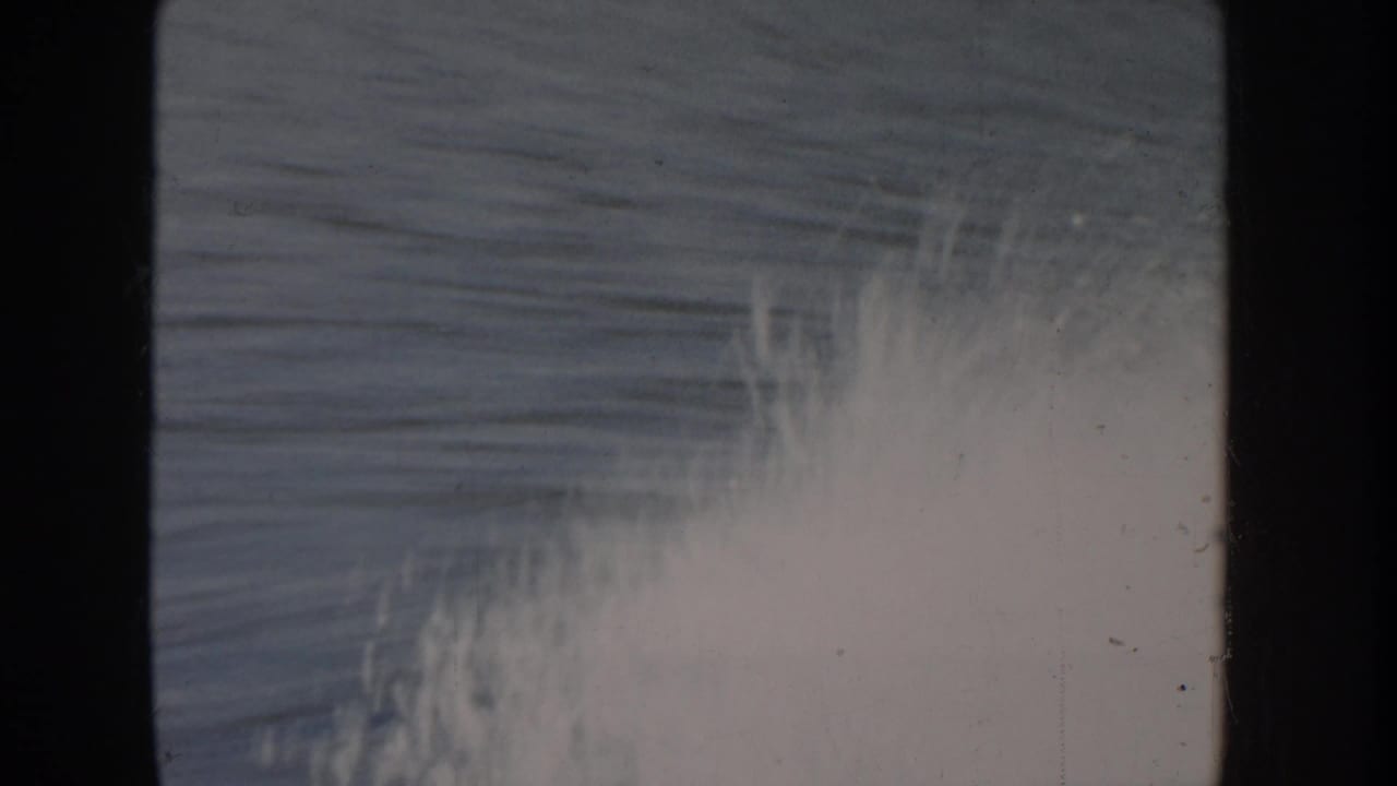 Opening frame of Idaho lake footage circa 1955, severely overexposed with film flare and diagonal scratch marks across the 8mm emulsion.