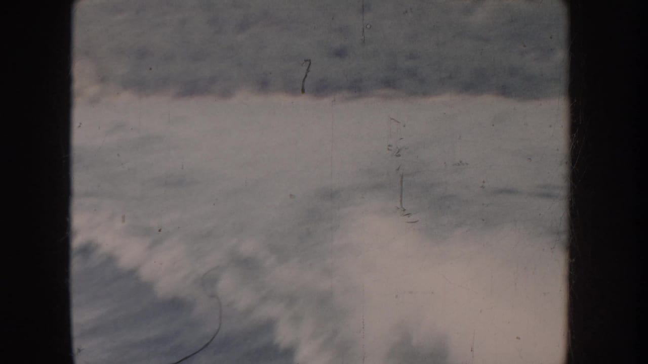 Breaking ocean or lake waves with white foam filmed on 8mm stock; cool desaturated tones suggest significant color fading, possibly mid-1950s