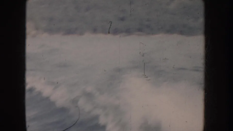 Breaking ocean or lake waves with white foam filmed on 8mm stock; cool desaturated tones suggest significant color fading, possibly mid-1950s