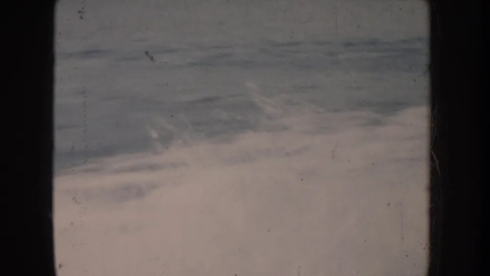 Rolling waves with white spray filmed on 8mm home movie stock; cool desaturated palette indicates significant emulsion fading consistent with mid-century film age