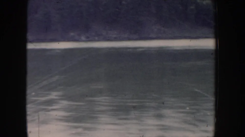Boat wake on an Idaho lake, 1955 home movie; blue-violet color shift and prominent white wake band show both vessel motion and the film stock's age.
