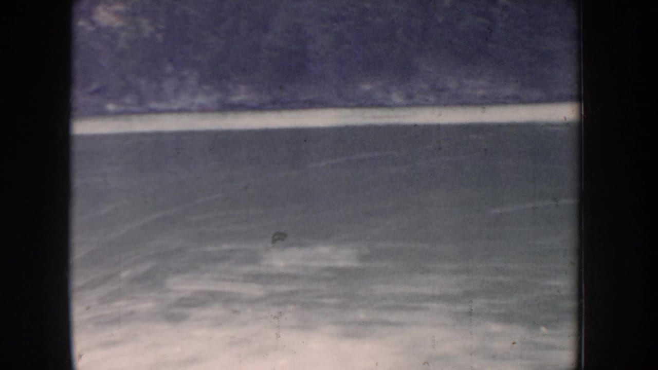 First-person view of turbulent river water and foam wake from a speedboat, circa 1955 Idaho, showing blue-grey color shift of aged 8mm stock.