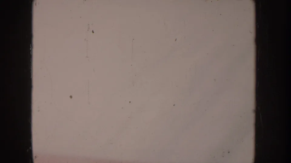 Essentially blank frame from aged 8mm stock showing severe overexposure or color reversal failure; film grain, dust spots, and faint vertical scratches remain visible.