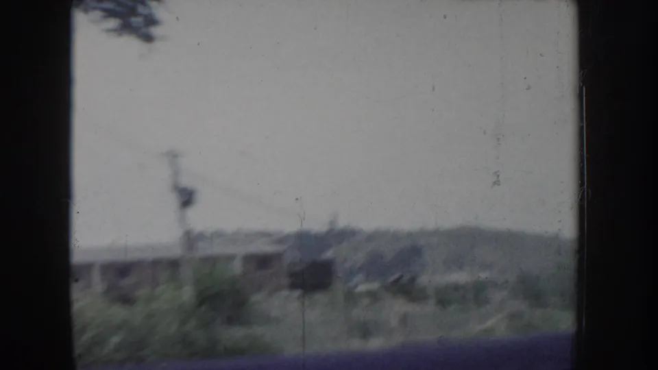 Overexposed 8mm frame, likely Idaho circa 1955, showing utility poles, sparse grass, and a barely legible distant landscape.