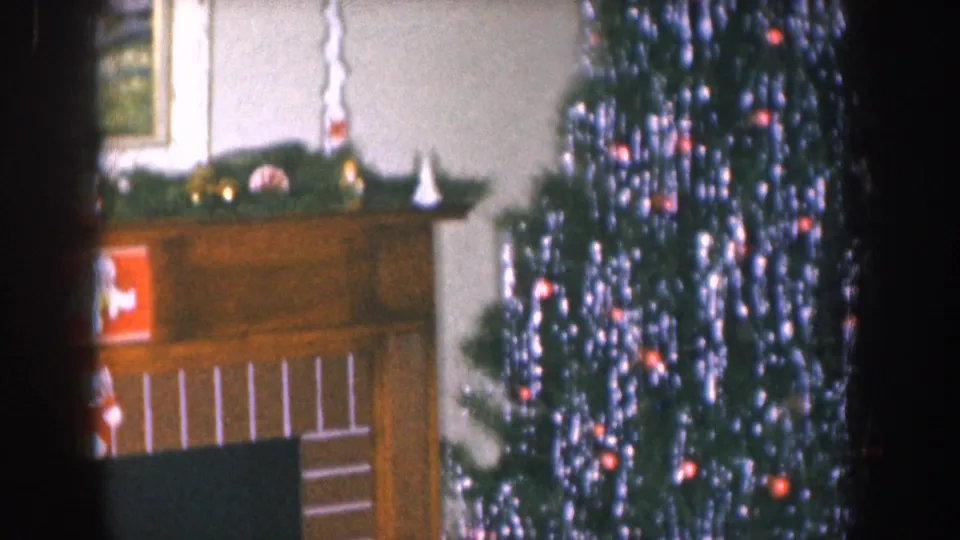 8mm home movie circa 1955 Nebraska; wood fireplace mantel with pine garland, small white figurines, and framed painting above; Santa Claus decoration visible at lower left.
